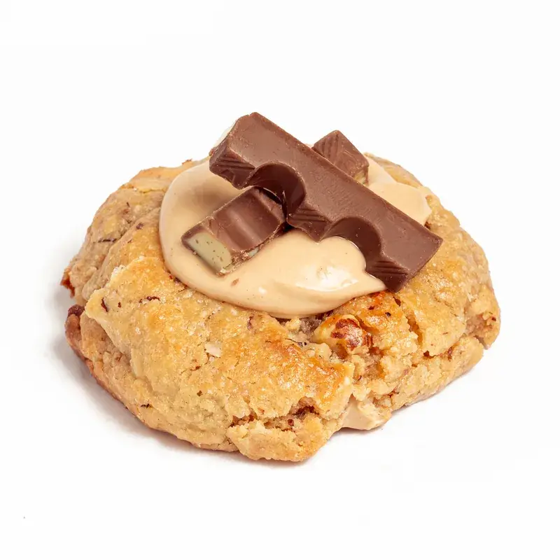 Cookie con crema de avellana y onzas de chocolate Kinder por encima, sobre fondo blanco