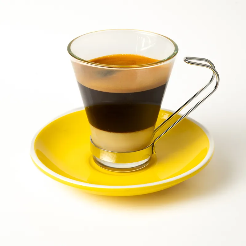 Café bombón en vaso de cristal con asa metálica, con la capa de leche condensada y el café