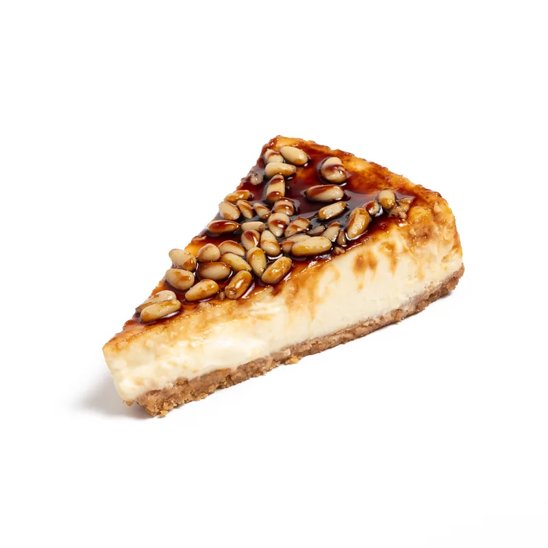 Porción de tarta de queso Carapino con piñones y caramelo por encima