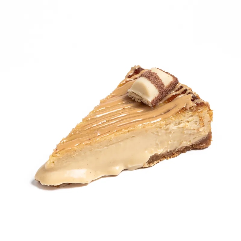 Porción de tarta de queso de Kinder Bueno con hilos de crema y un trozo de barrita Kinder Bueno
