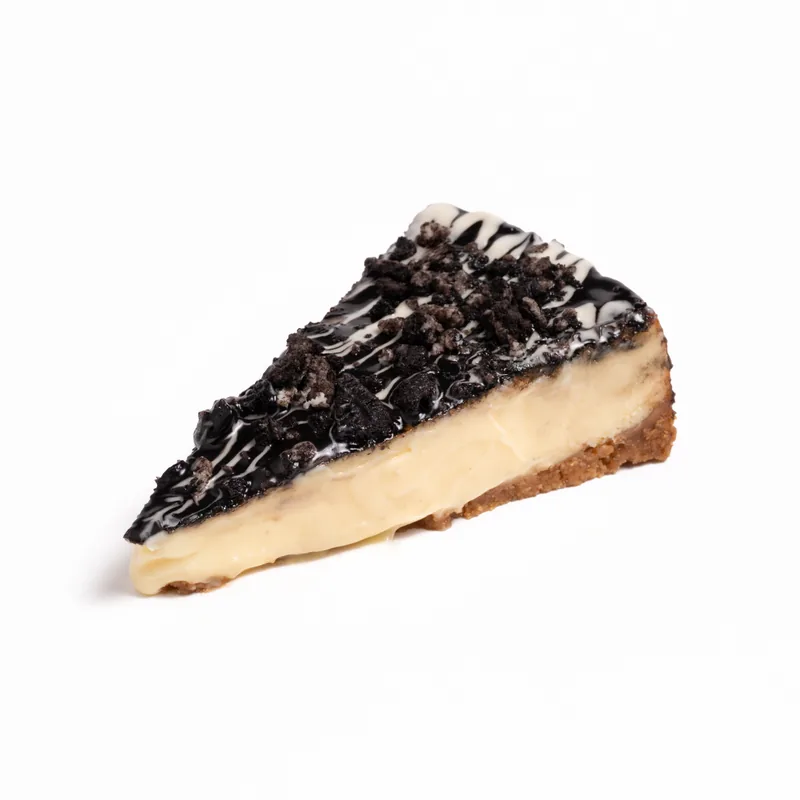 Porción de tarta de queso de Oreo blanco con galleta Oreo triturada e hilos de chocolate blanco sobre interior claro